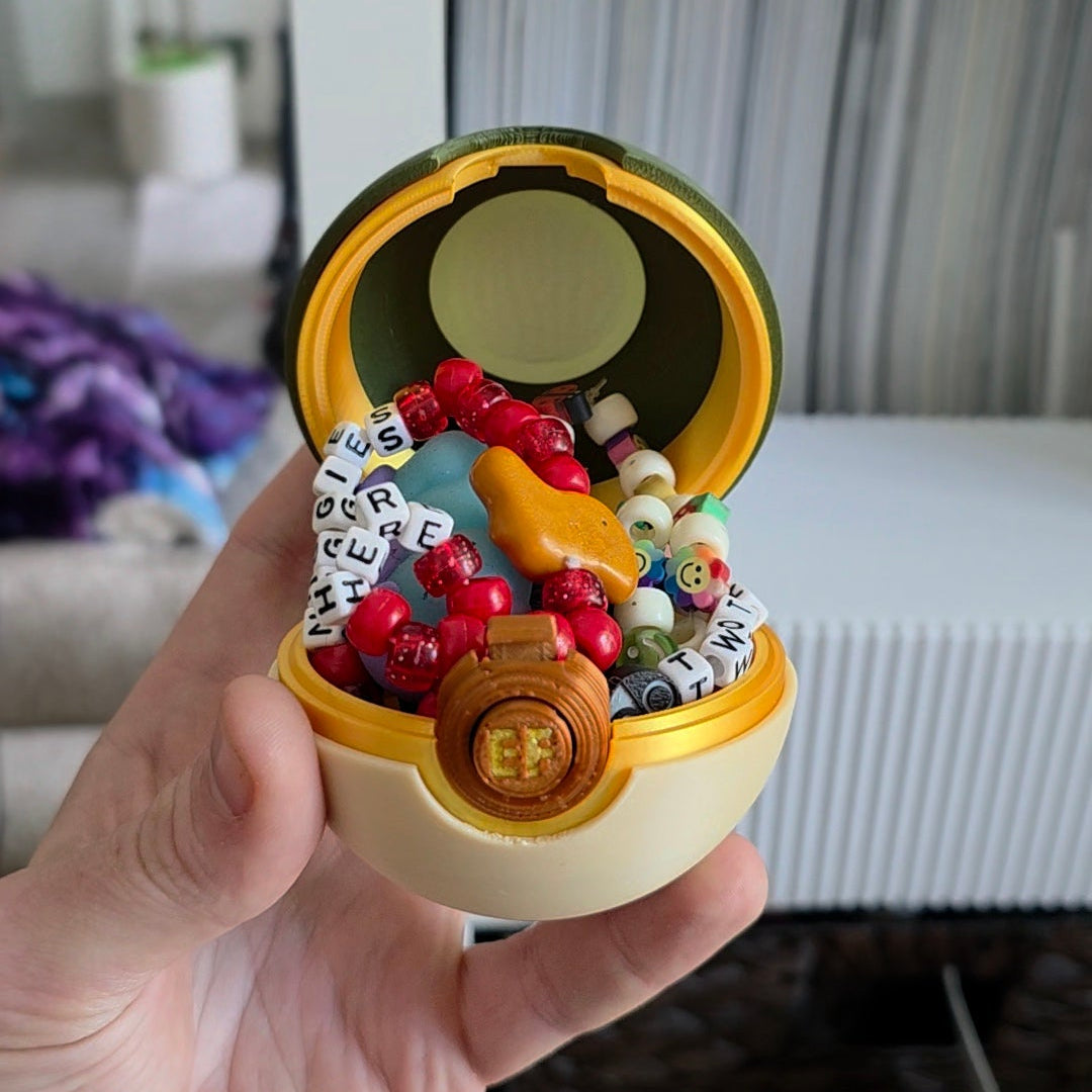 A hand holding an open Pokémon-themed jewelry box filled with colorful beaded necklaces and bracelets, set against a blurred indoor background.