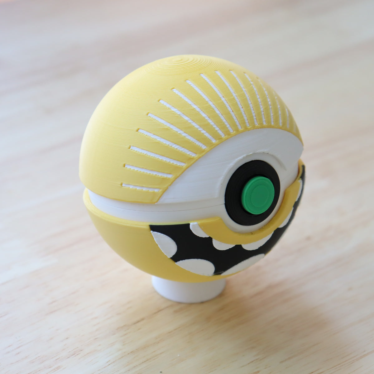Angled view of the Cyclops Memory Capsule showing the radiating white eye details, green button, and black-and-white mouth.