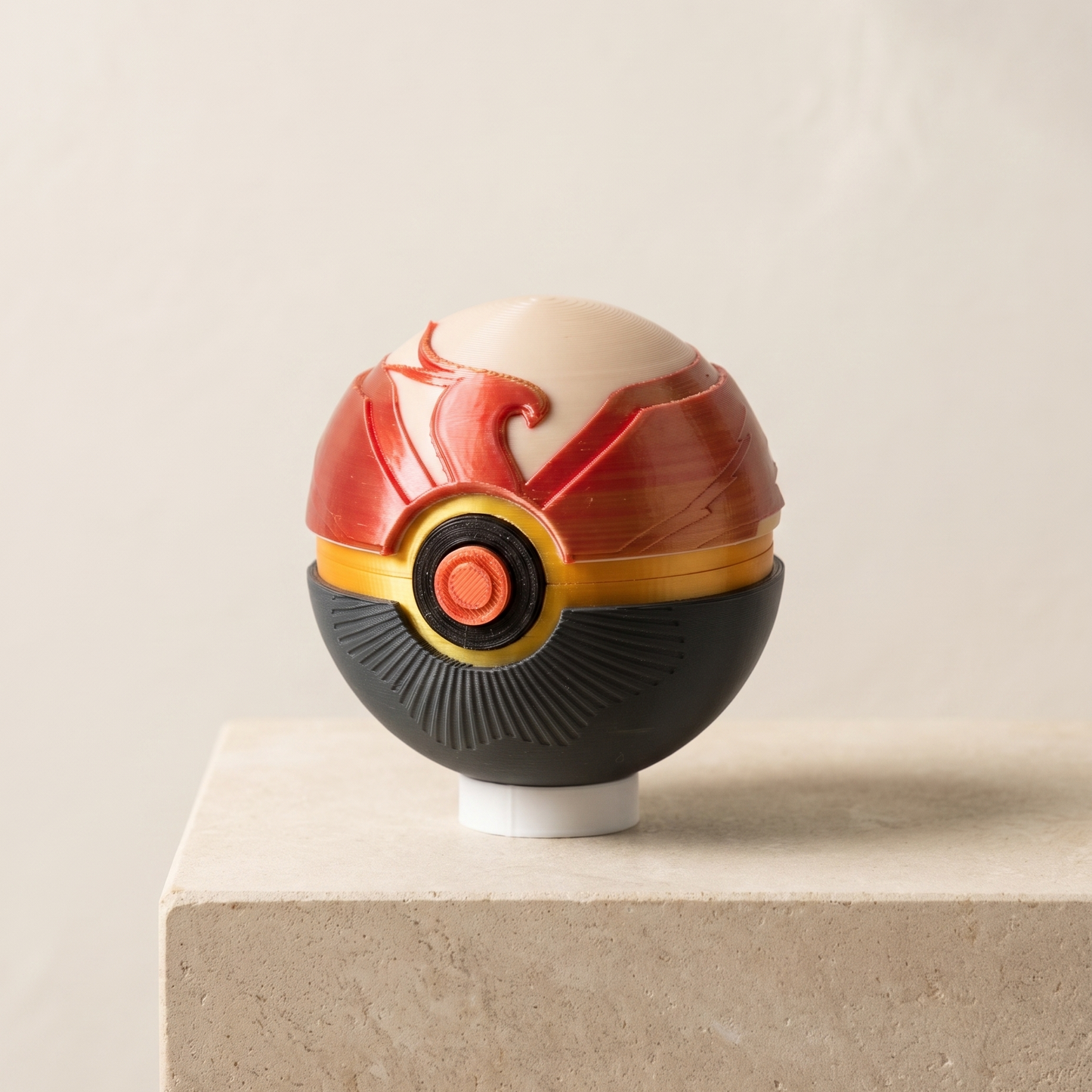 A stylized spherical decorative object resembling a Pokéball-inspired design, with a cream top, red upper section, black lower section, and gold ring details, displayed on a beige pedestal against a light neutral background.